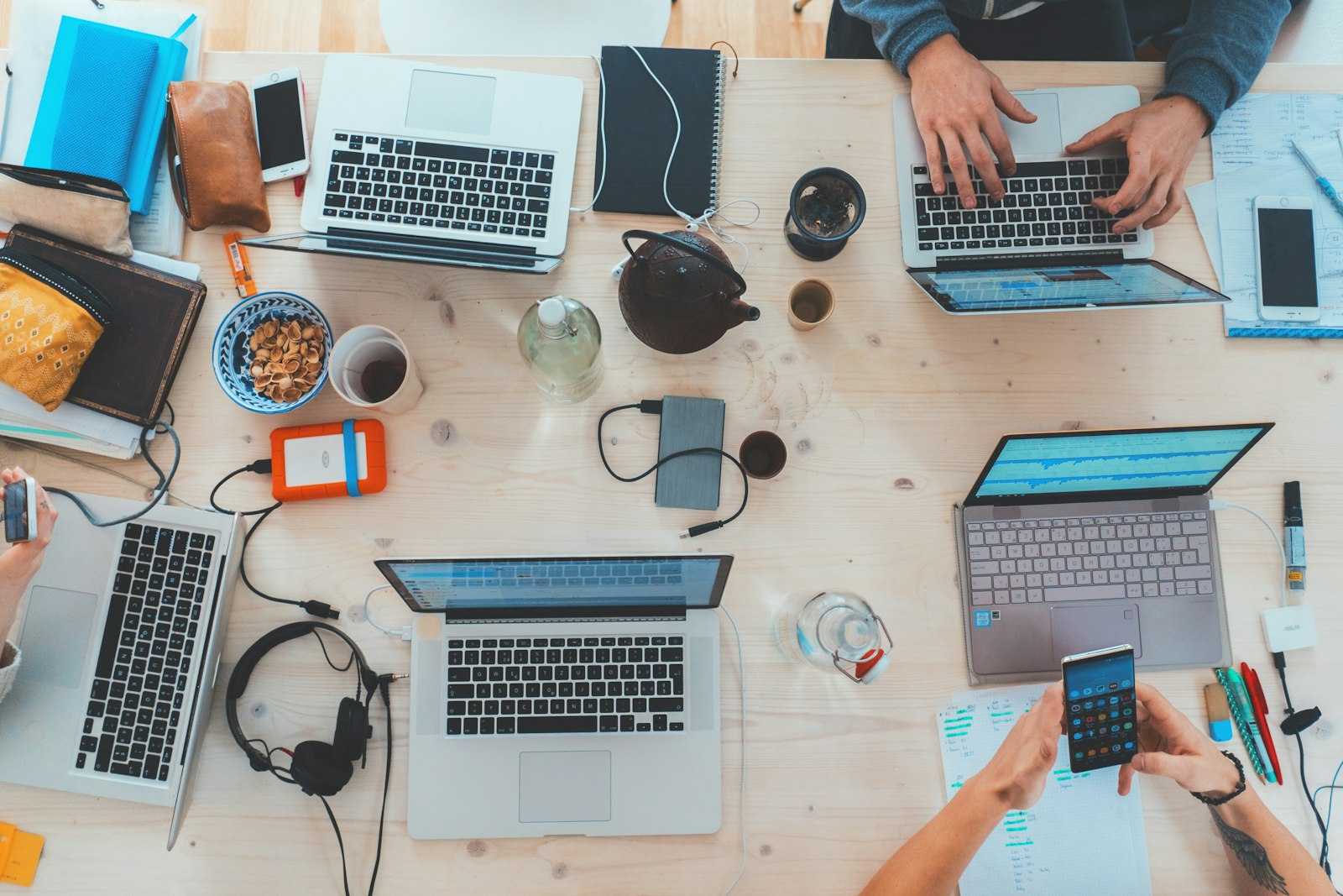 A team working together across laptops and phones at a shared desk