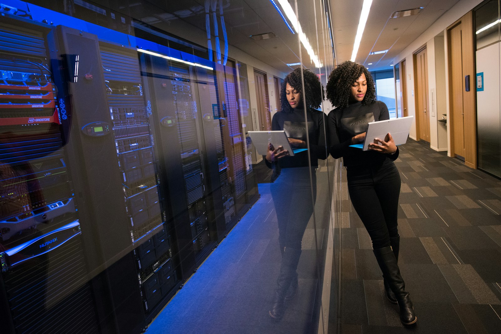 An engineer reviewing infrastructure on a laptop beside a server room
