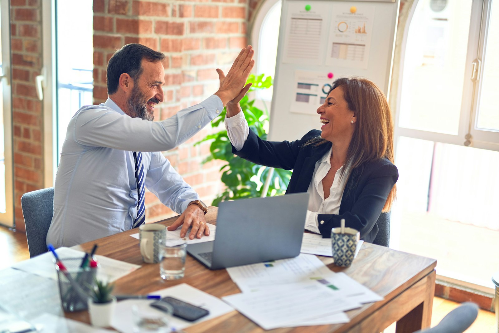 Two colleagues high-fiving in an office